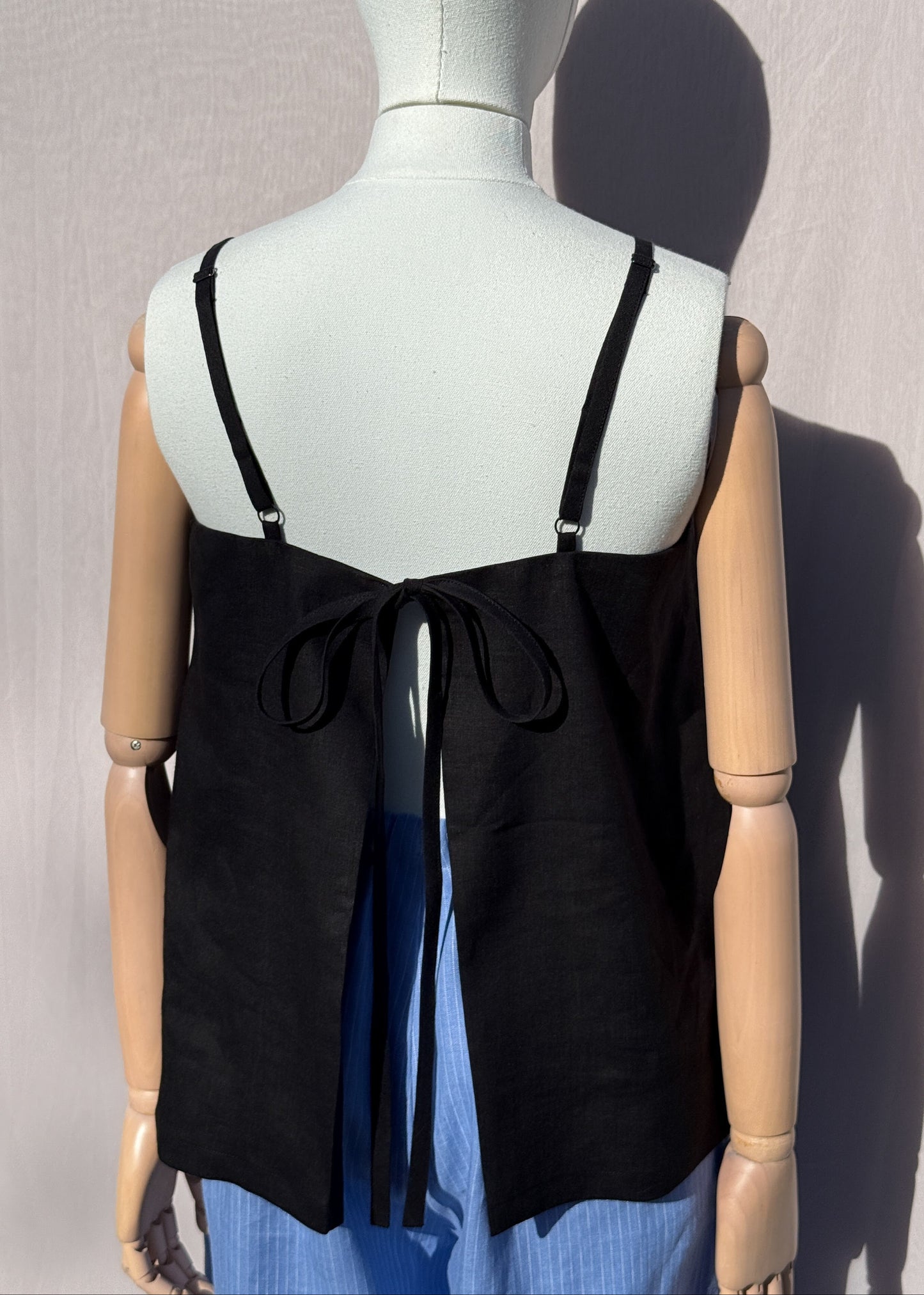 Black linen top on a mannequin in front of a plain beige background