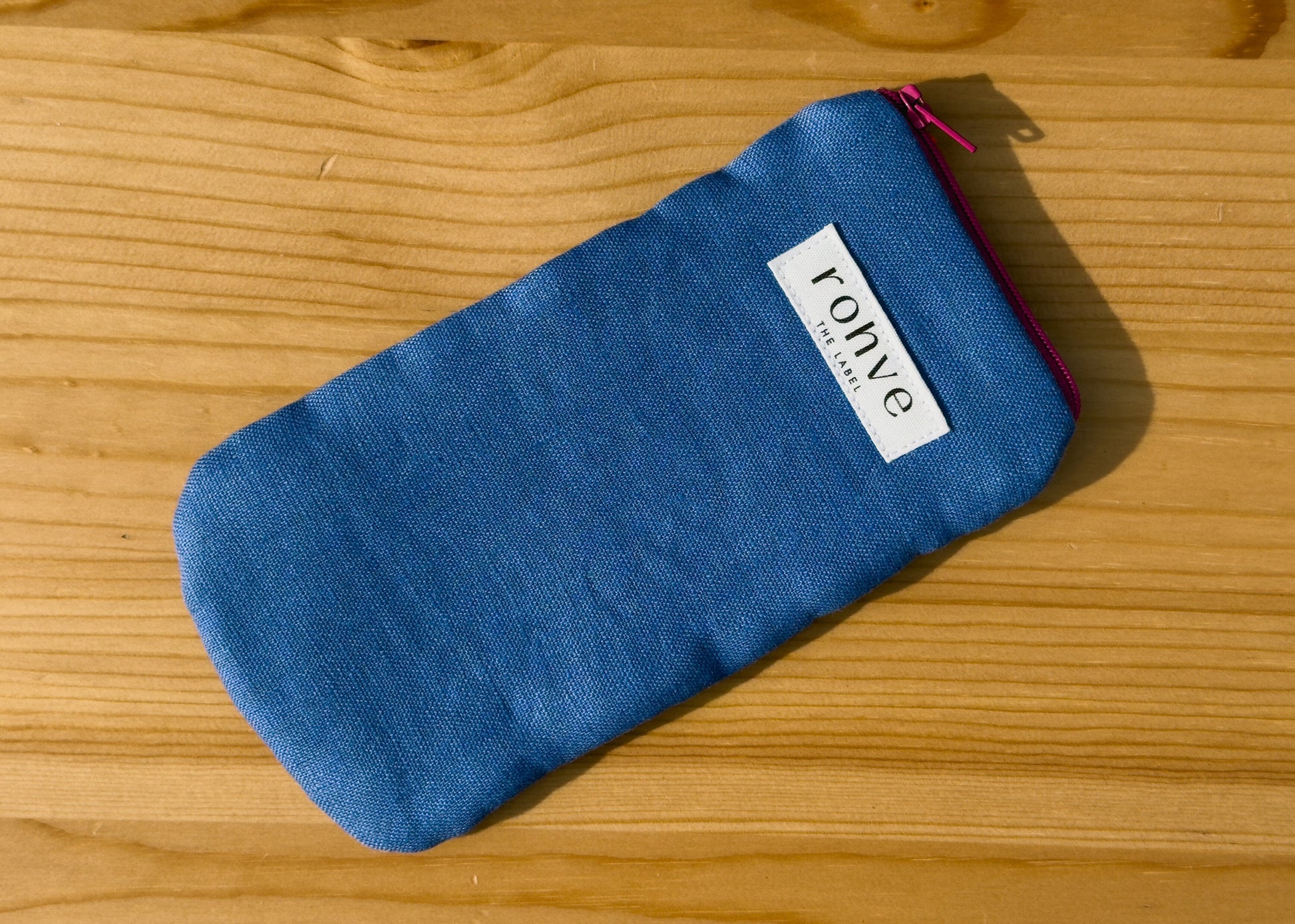 Blue striped pouch with a brand label on a wooden background