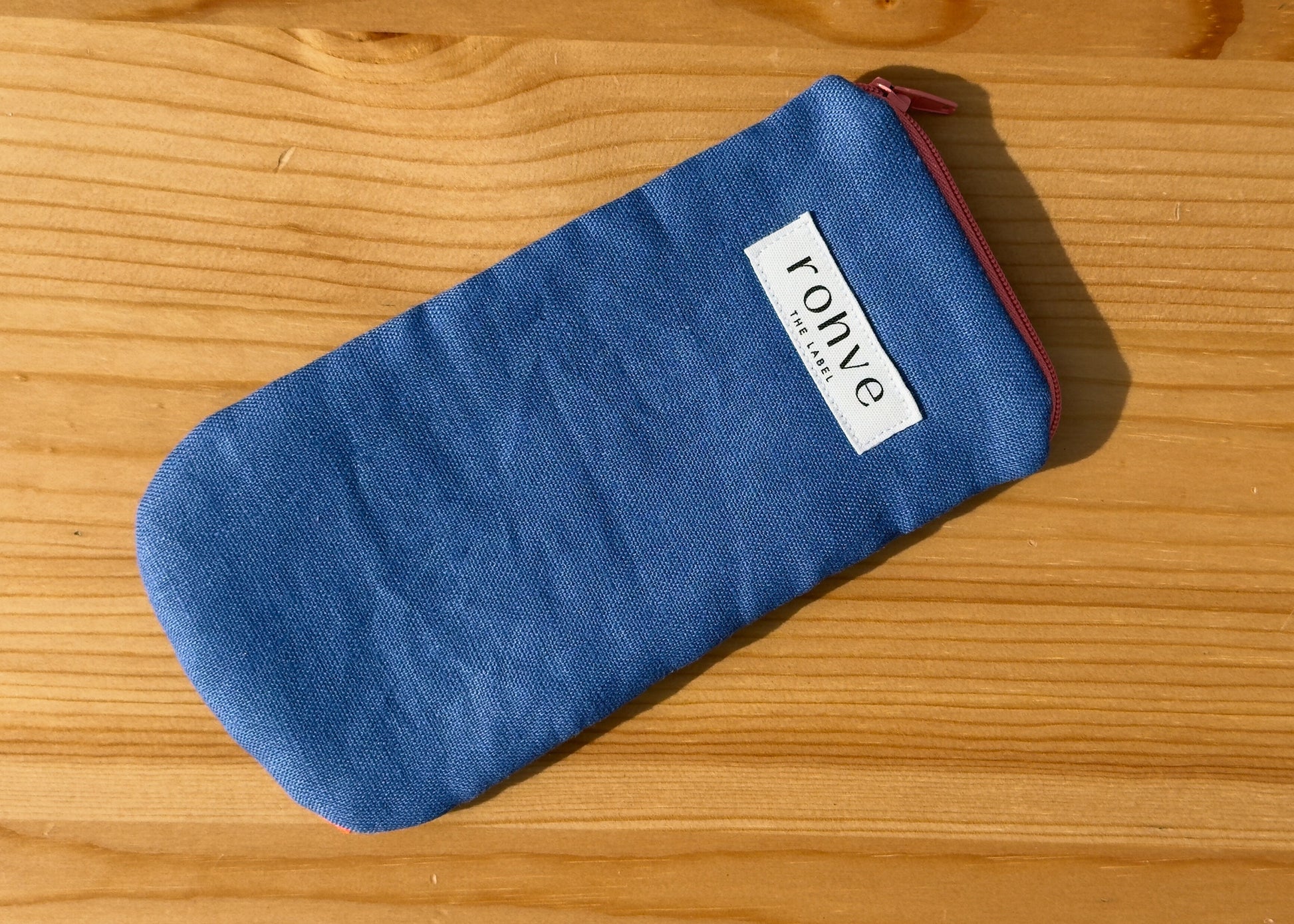 Blue striped pouch with a brand label on a wooden background
