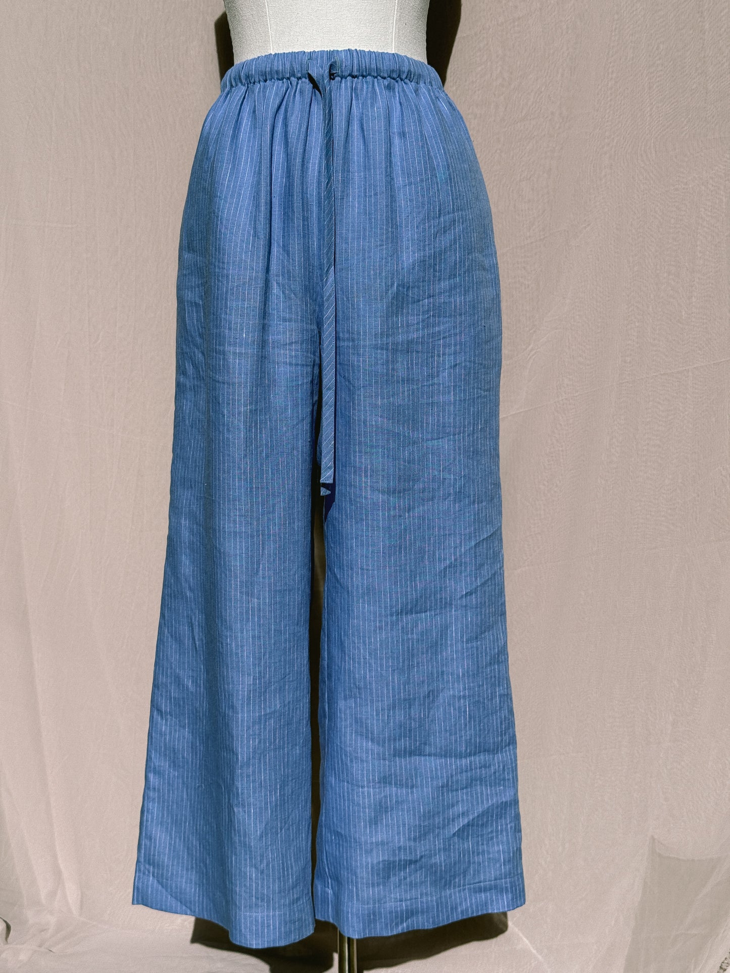 Blue striped wide-leg pants with waist tie on a mannequin against a plain background