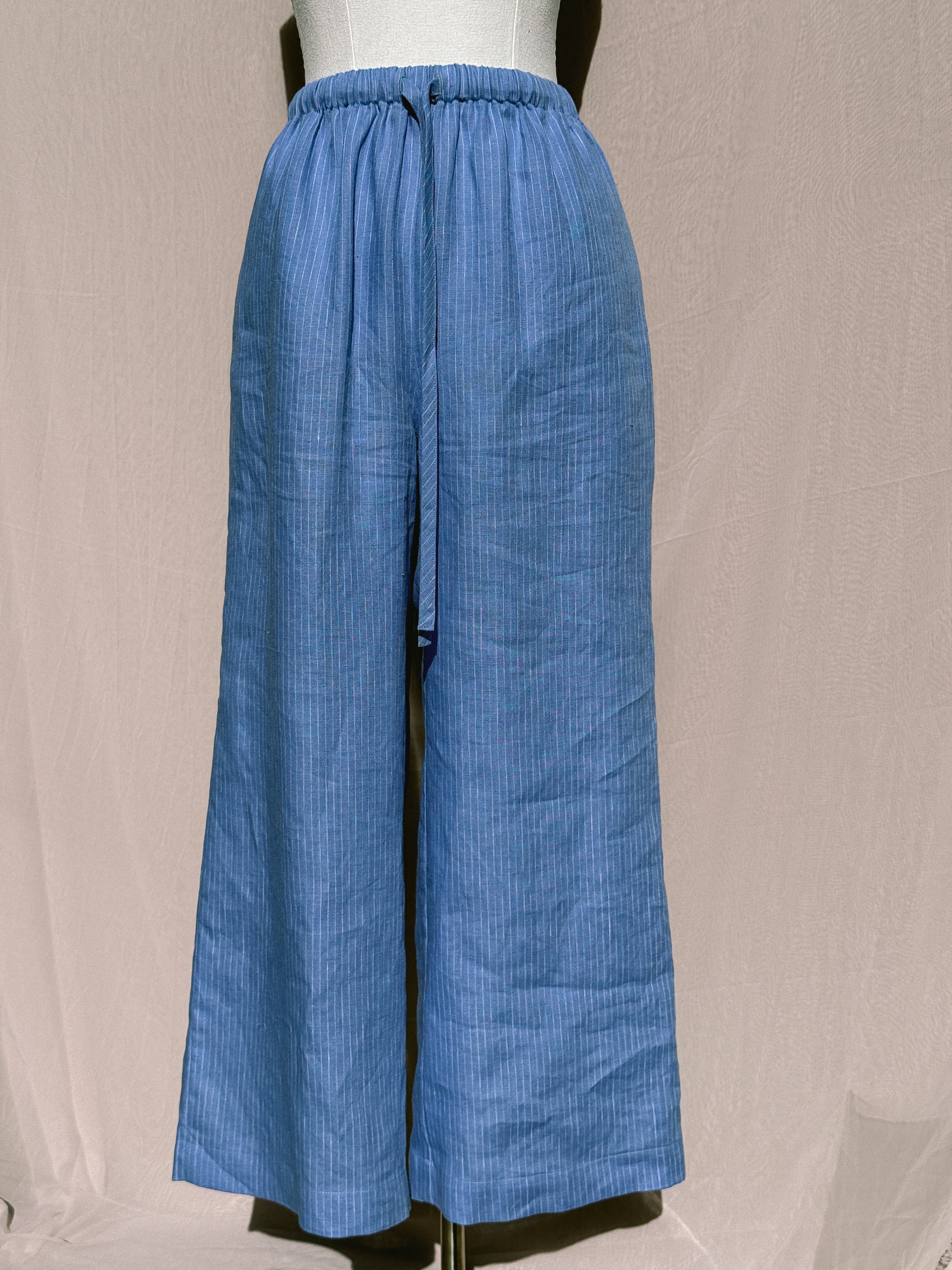 Blue striped wide-leg pants with waist tie on a mannequin against a plain background