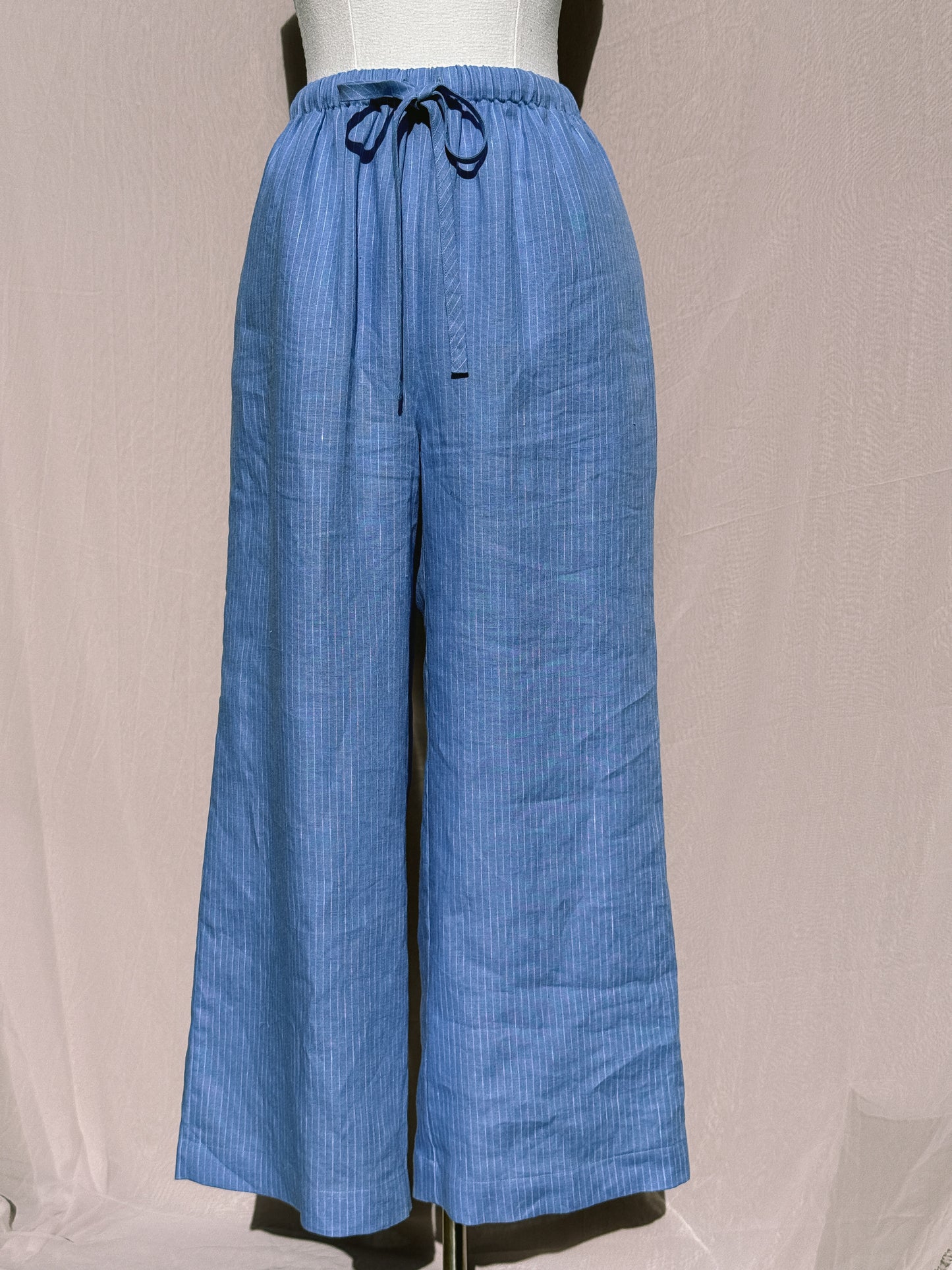 Blue stripe wide-leg pants with waist tie on a mannequin against a plain background