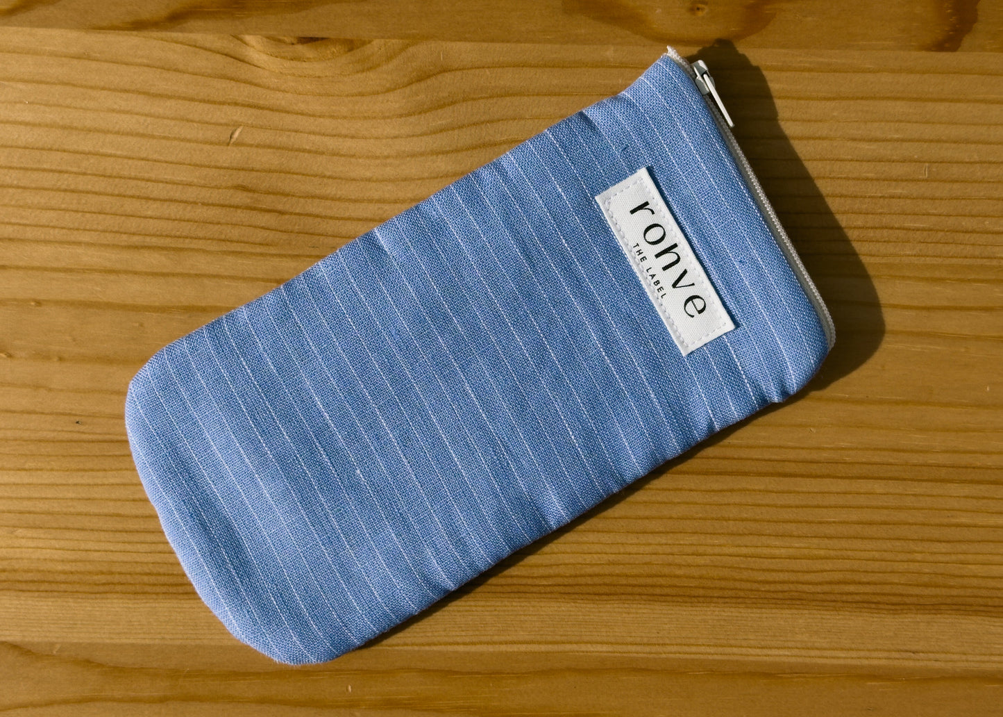 Blue striped pouch with a brand label on a wooden background