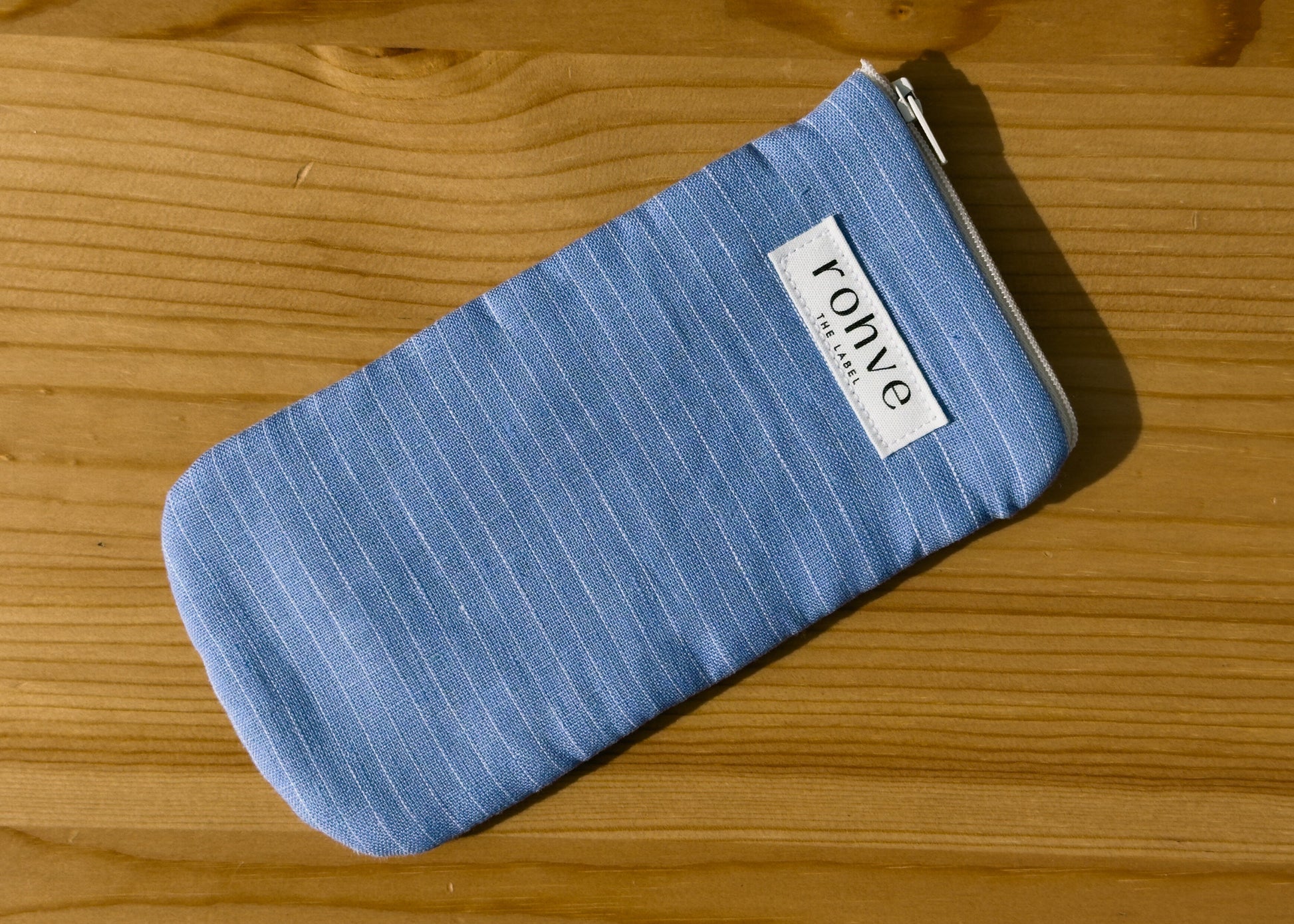 Blue striped pouch with a brand label on a wooden background