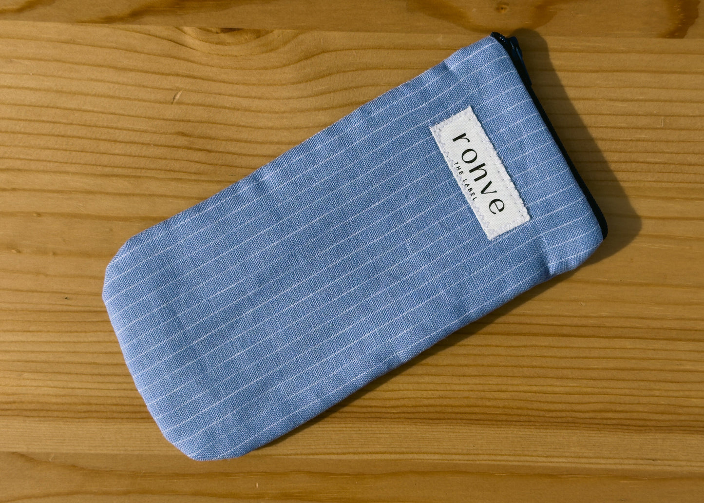 Blue striped pouch with a brand label on a wooden background