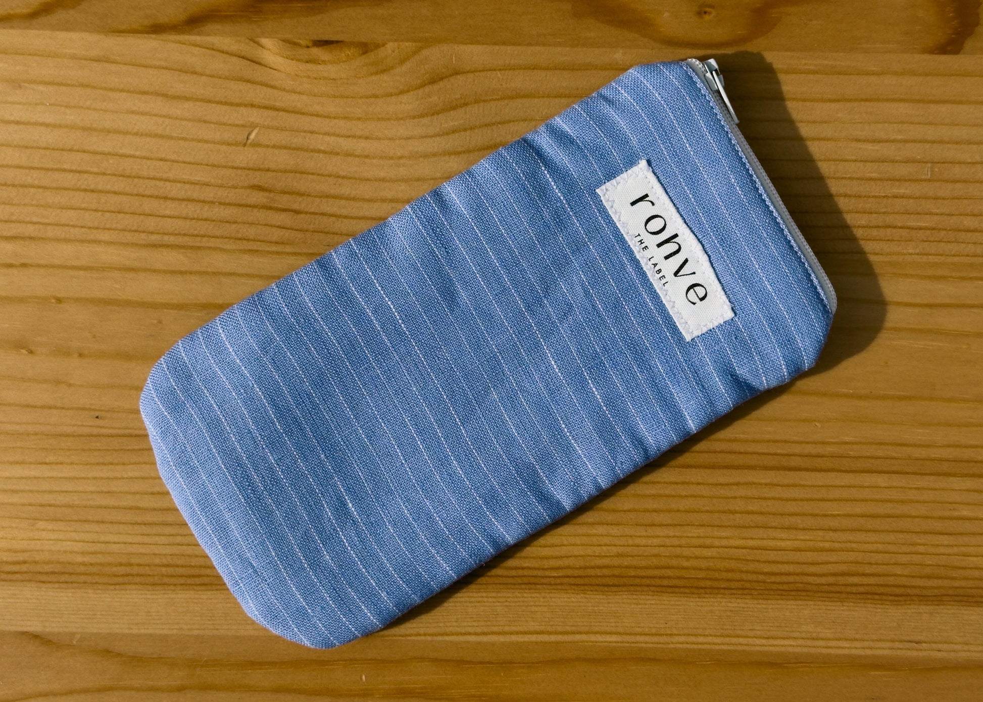 Blue striped pouch with a brand label on a wooden background