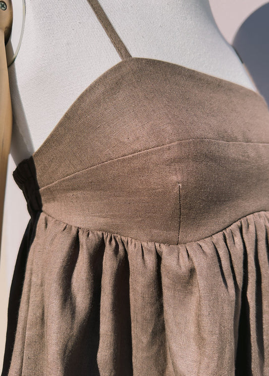 Close up brown linen top with gathers on a mannequin in front of a plain beige background