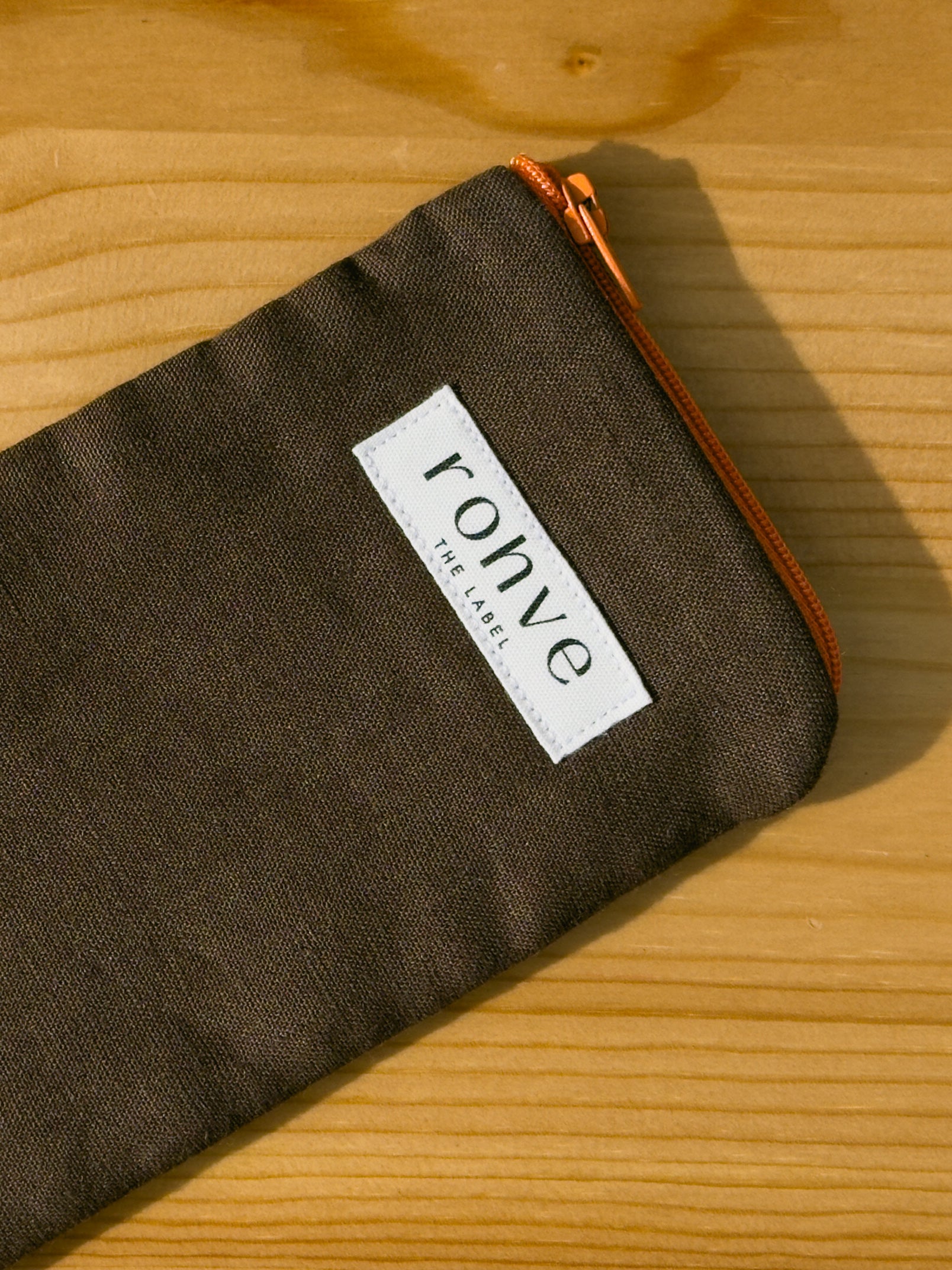 Brown pouch with a brand label on a wooden background