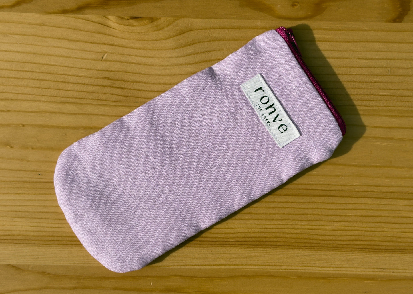 Lilac striped pouch with a brand label on a wooden background