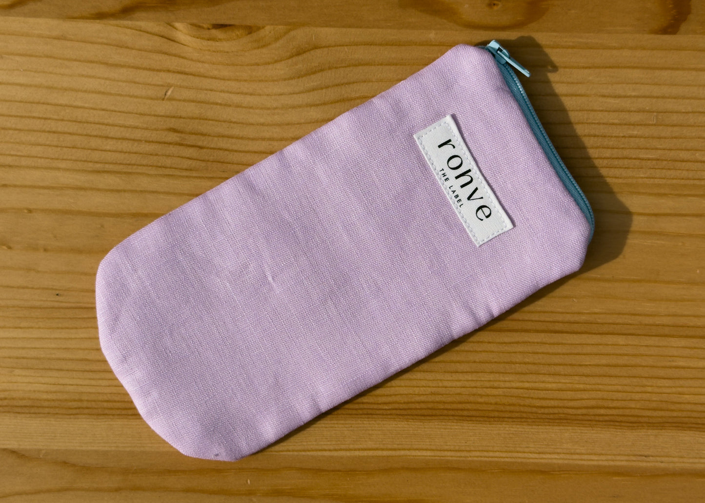 Lilac striped pouch with a brand label on a wooden background
