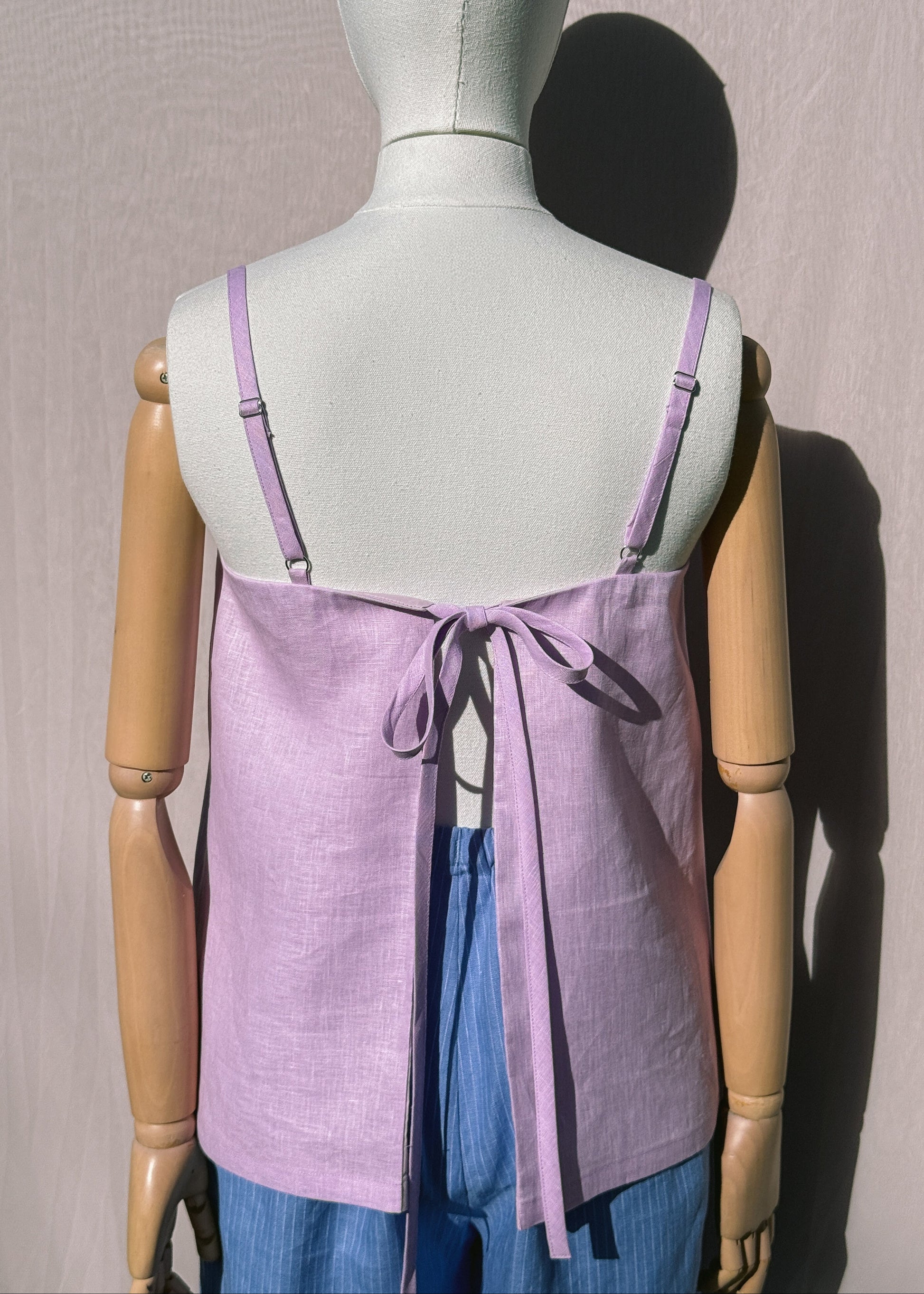 Lilac linen top with back tie on a mannequin in front of a plain beige background