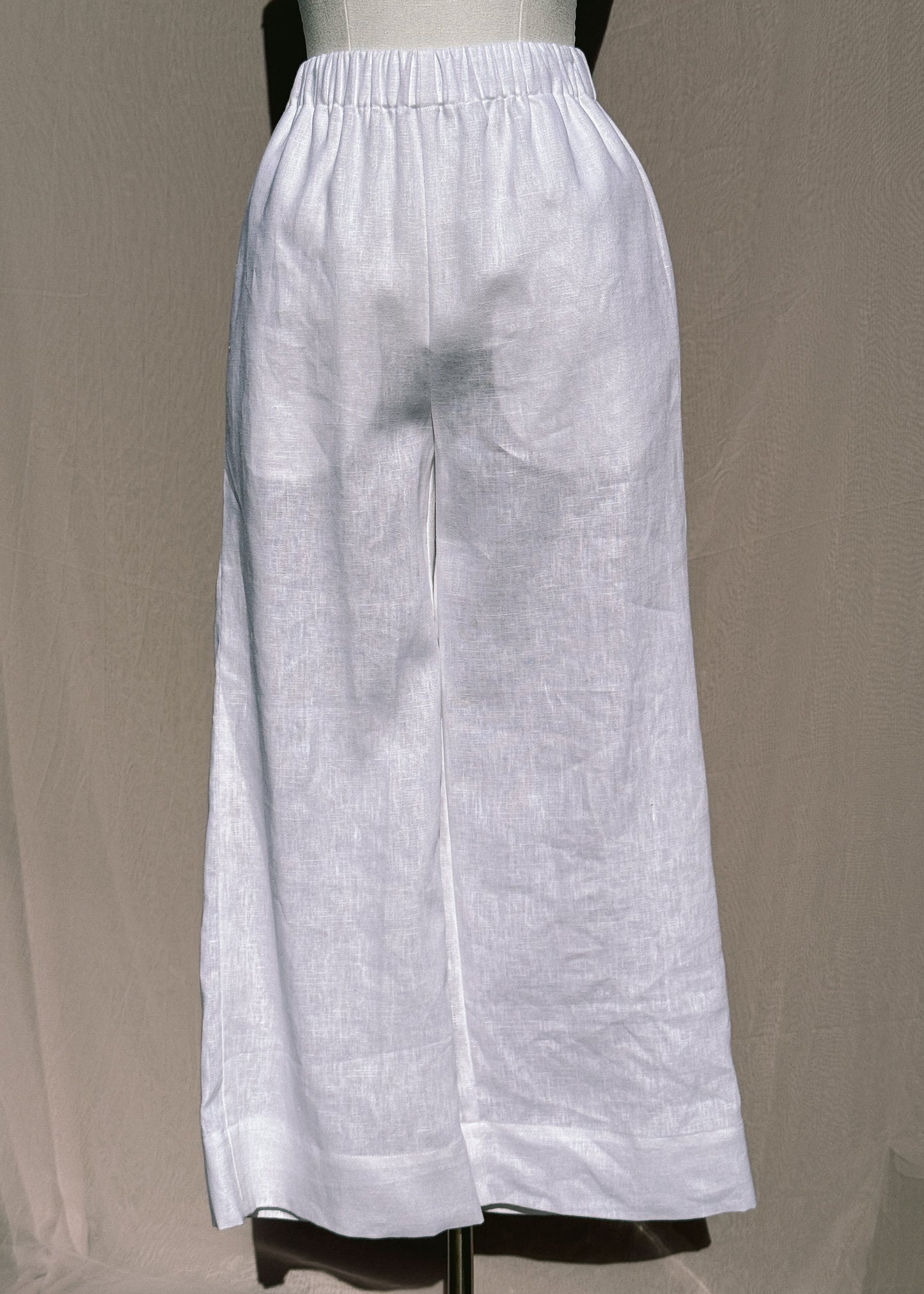 White wide-leg pants on a mannequin against a beige background