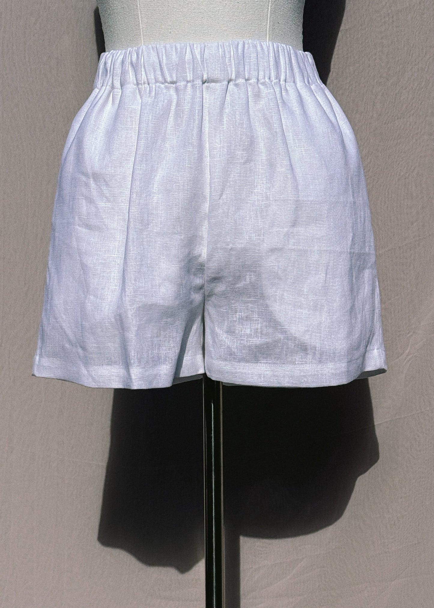 White linen shorts on a mannequin against a plain background