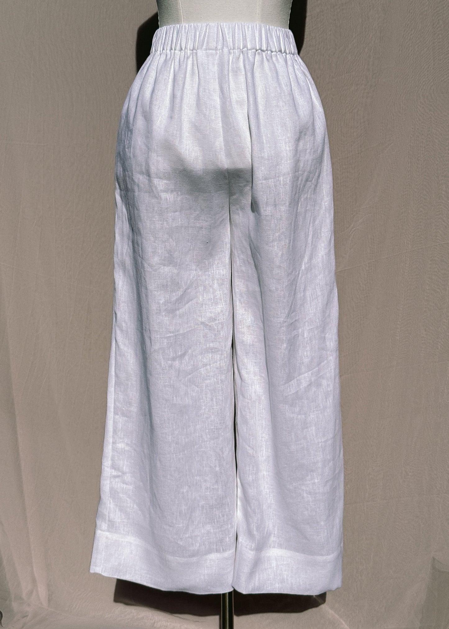 White wide-leg pants on a mannequin against a beige background