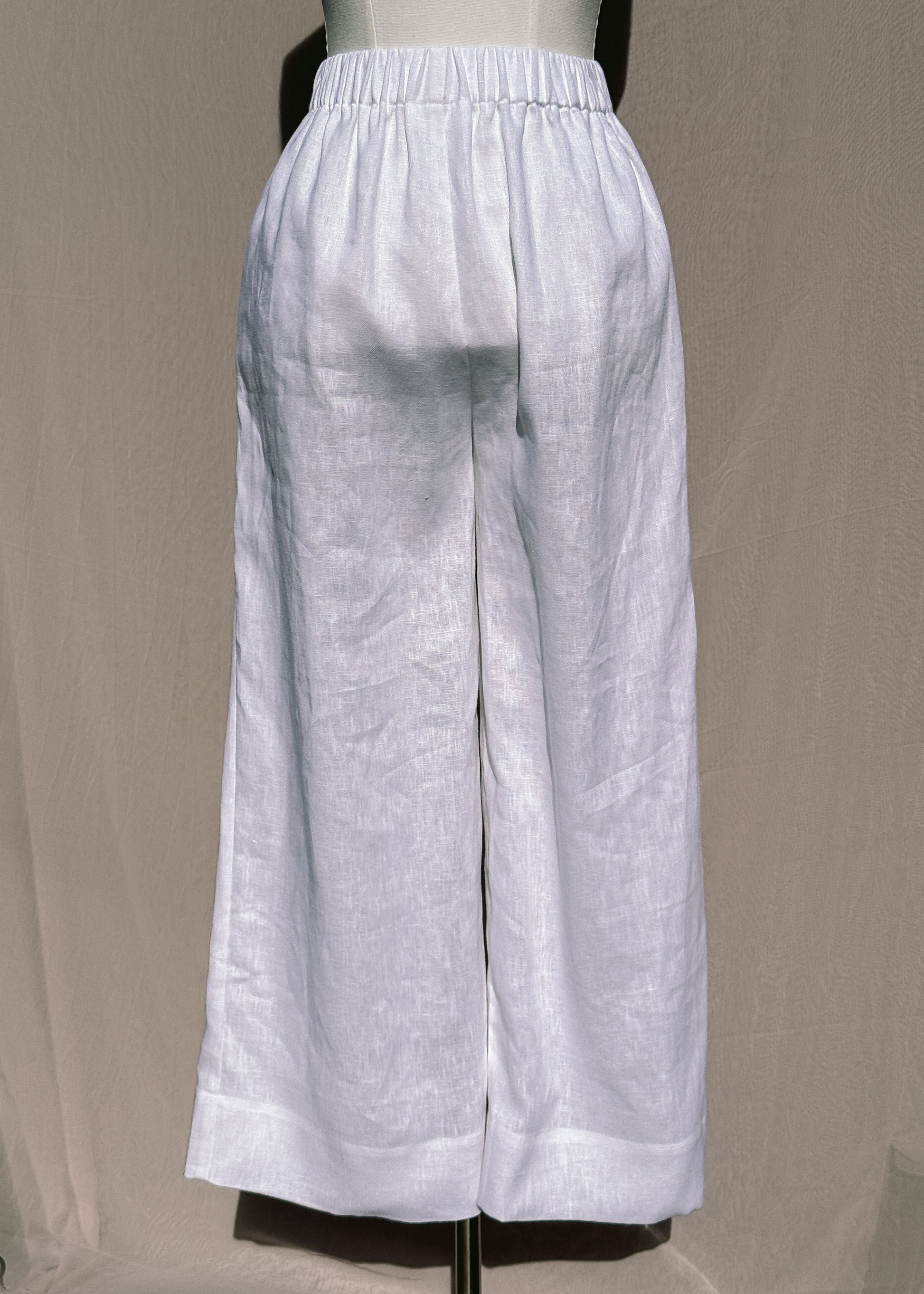 White wide-leg pants on a mannequin against a beige background