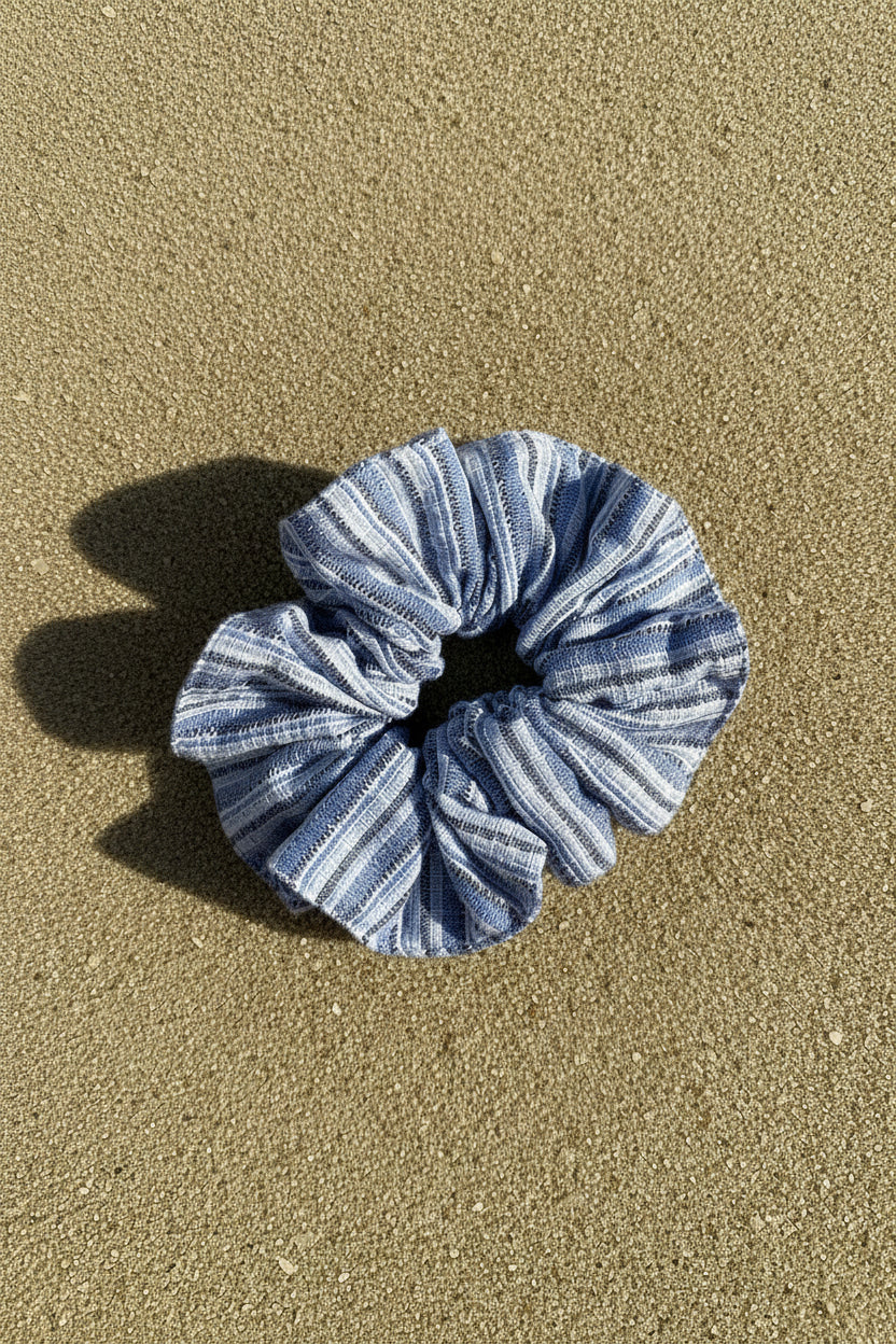 A fabric scrunchie with a blue and white striped pattern, photographed from above.