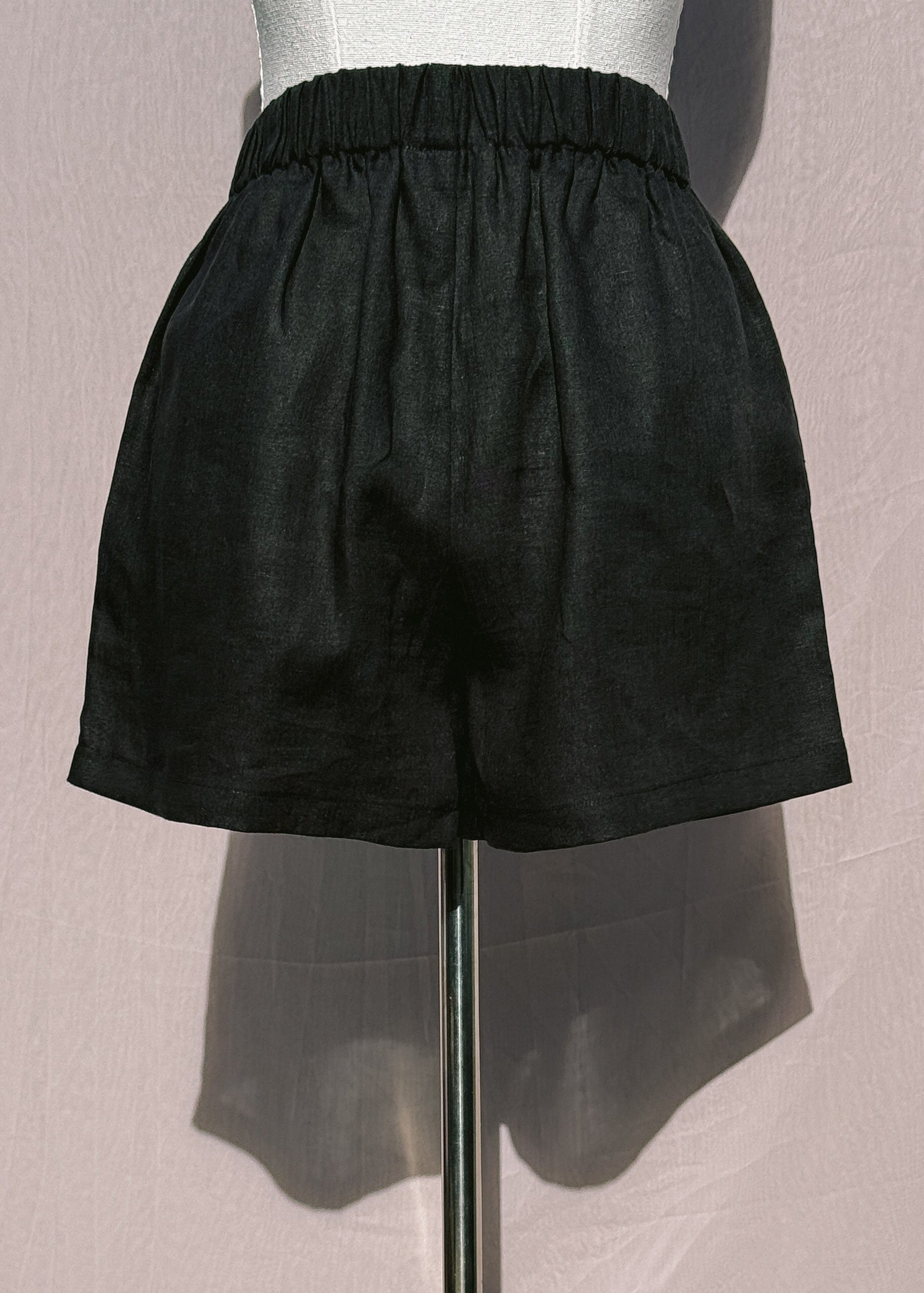 Black linen shorts on a mannequin against a plain background