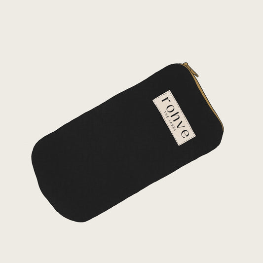 Black pouch with a brand label on a light beige background