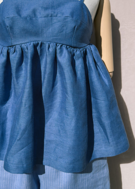 Blue linen top with gathers on a mannequin against a plain background cropped