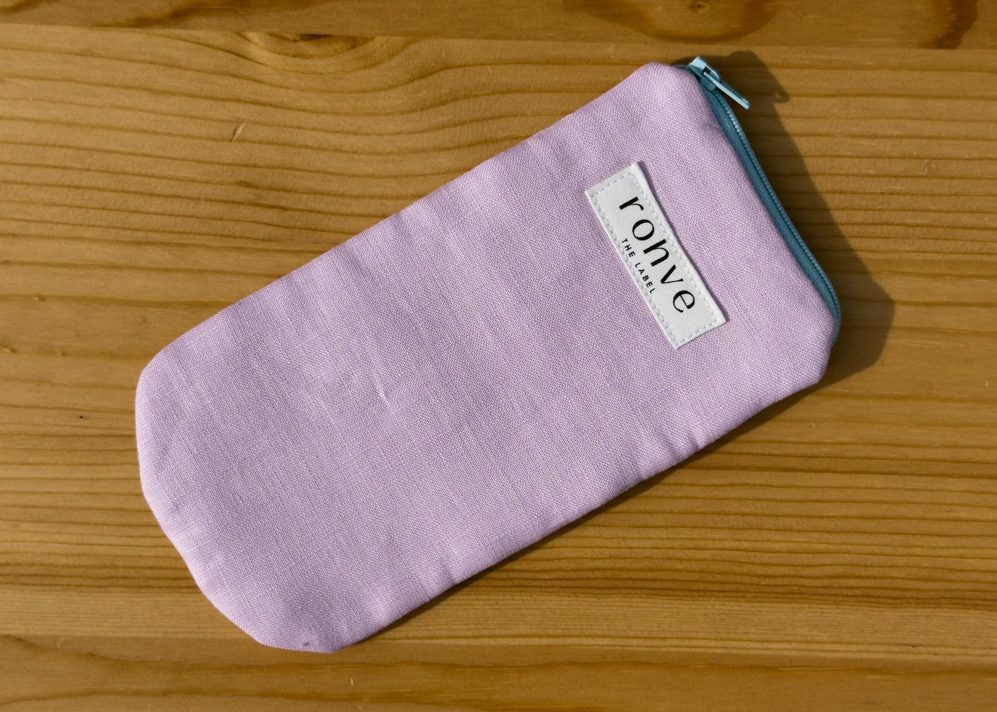 Lilac striped pouch with a brand label on a wooden background