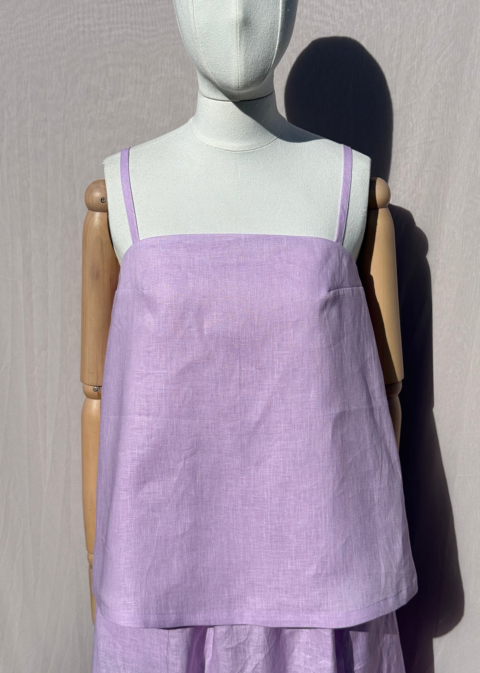 Lilac linen top on a mannequin in front of a plain beige background