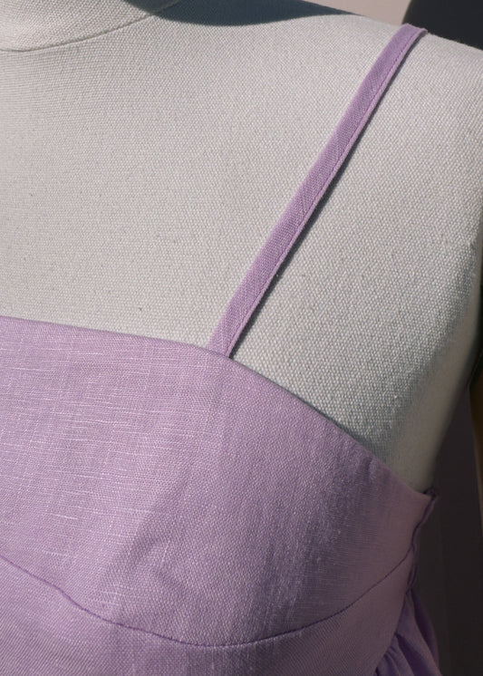 Close up of lilac linen top with gathers on a mannequin in front of a plain beige background