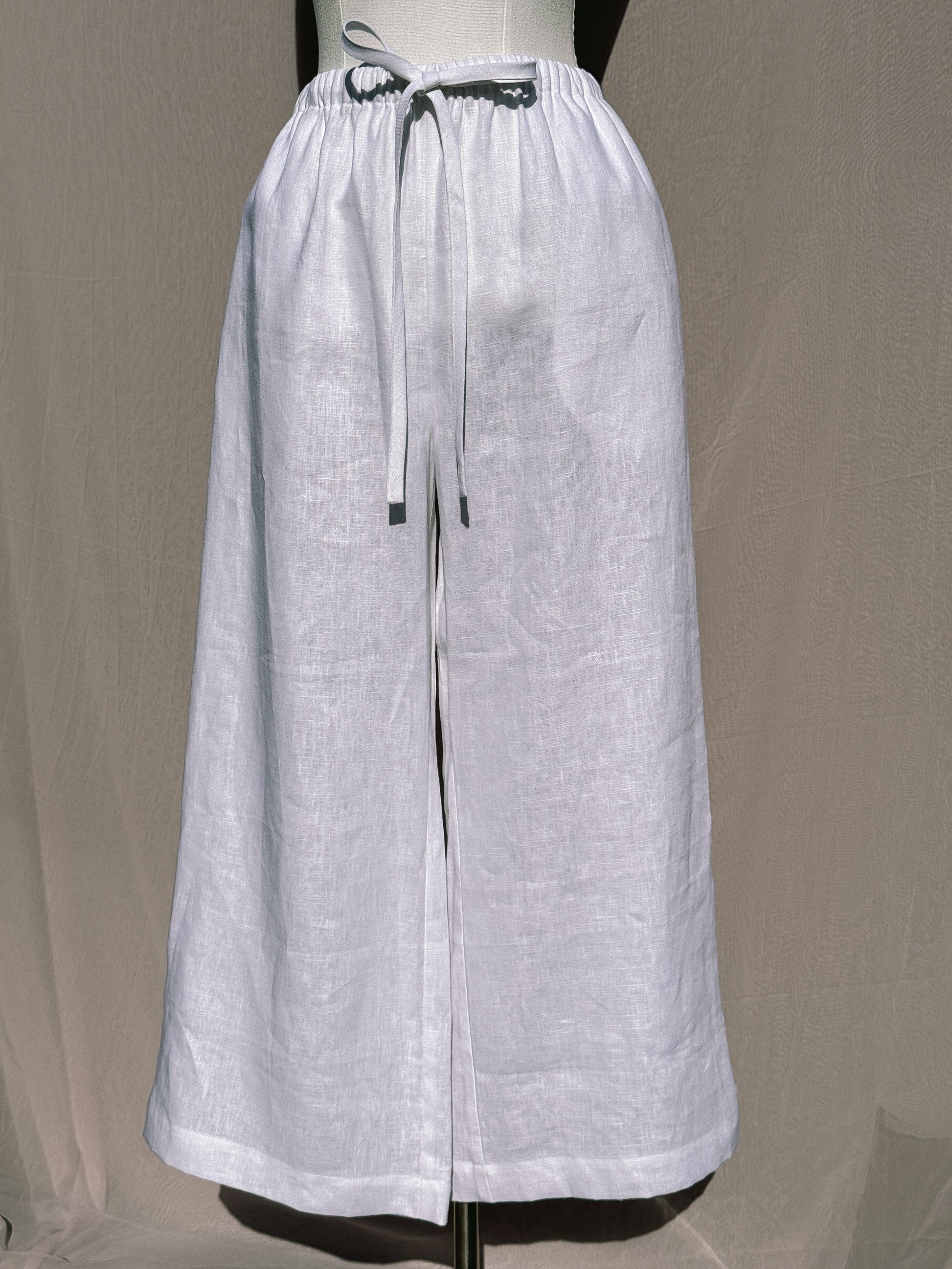 White wide-leg pants with waist tie on a mannequin against a plain background